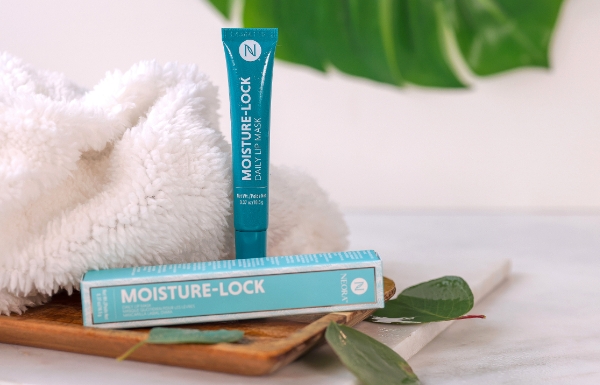 Neora’s Moisture-Lock Lip Mask on a wooden plate next to a hand towel